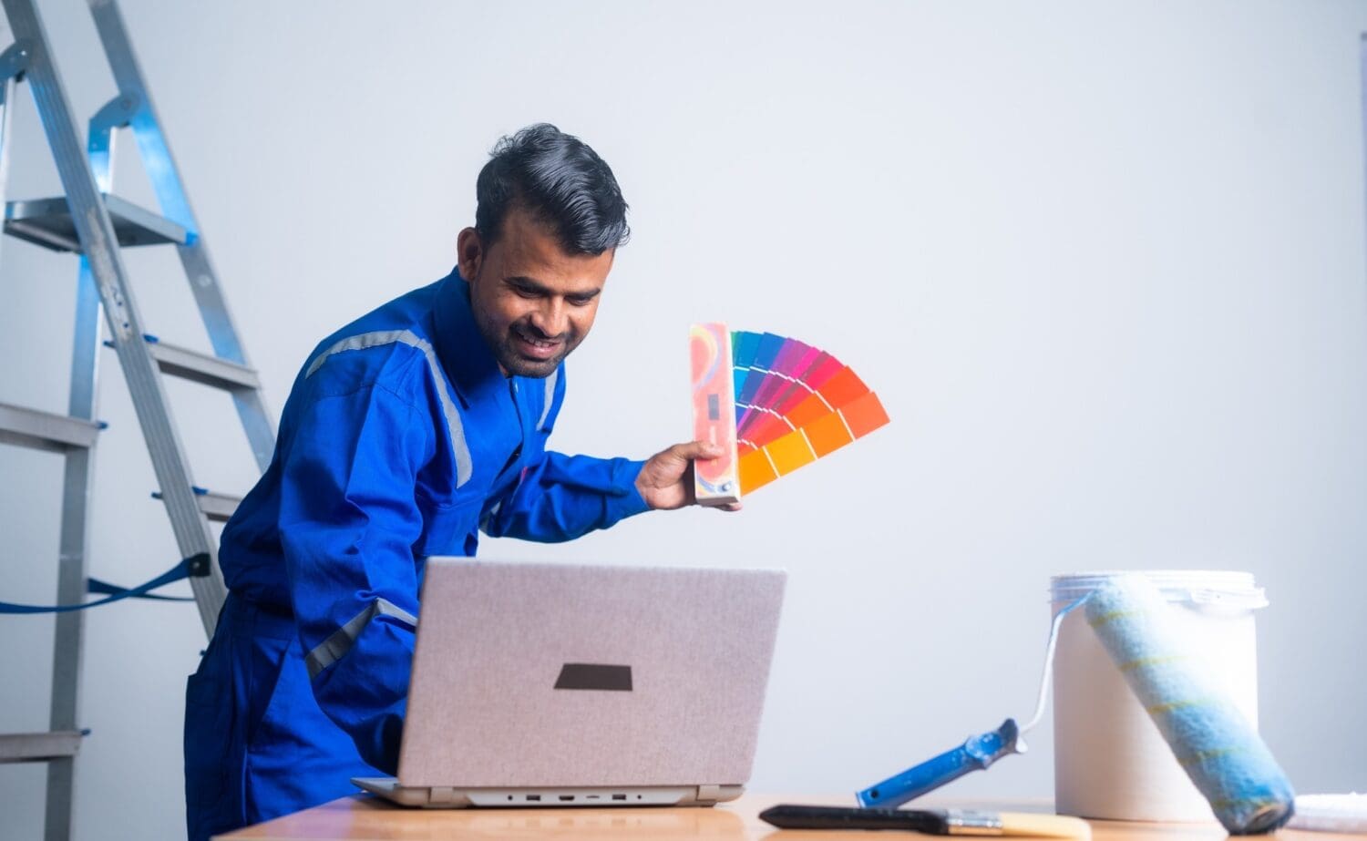 painter checking colour on laptop by holding color chart at apartment