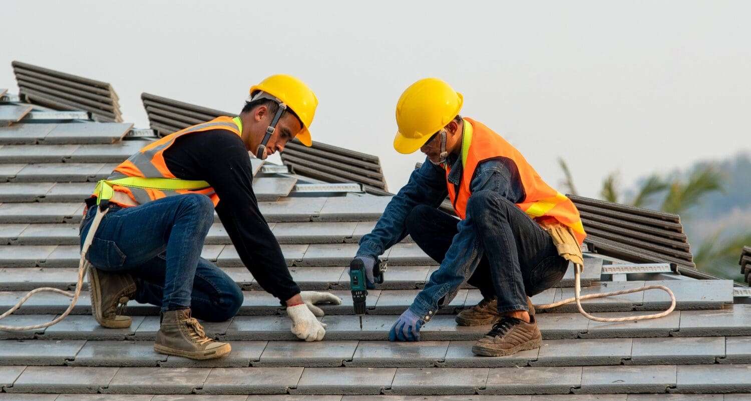 Construction worker wearing safety harness belt during working on roof structure of building on construction site
