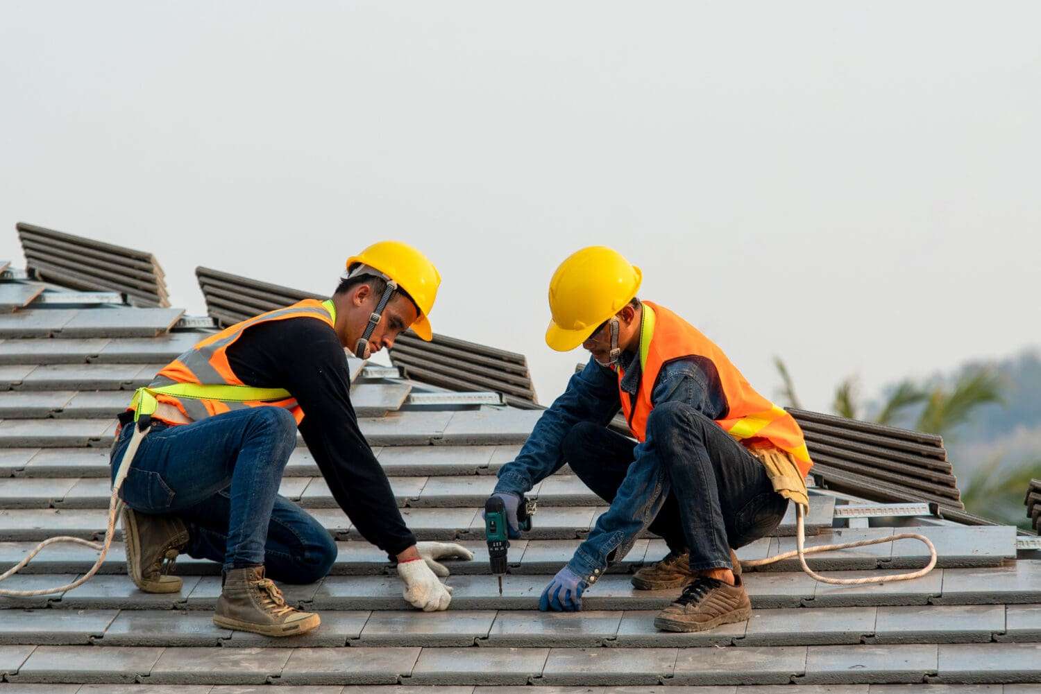 Construction worker wearing safety harness belt during working on roof structure of building on construction site